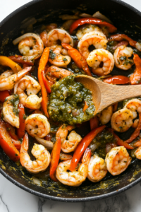This image shows salsa verde being stirred into the shrimp, creating a rich, tangy, and slightly spicy sauce.