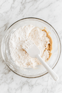 This image shows thick pumpkin bar batter being poured evenly into a greased and lined baking dish, ready for baking.