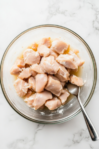 This image shows raw chicken pieces being fully submerged in a bowl of creamy buttermilk marinade, ensuring they soak up moisture and flavor.