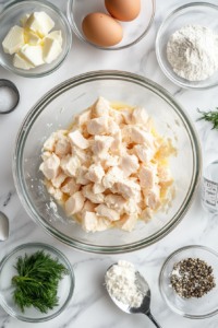 This image shows diced chicken being combined with cheese, eggs, and seasoning in a bowl to create a flavorful fritter mixture.