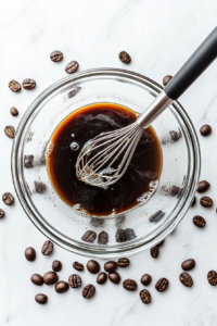 This image shows instant coffee, sugar, and water being combined in a mixing bowl, the first step in creating the rich and frothy whipped coffee topping.