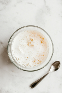 This image shows yeast being dissolved in warm milk with a touch of sugar, activating the yeast for a fluffy and well-risen Polish cheese babka.