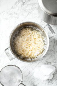 This image shows a pot of boiling water with noodles cooking until soft and tender.