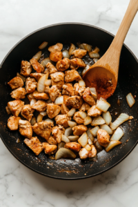 This image shows onions and garlic being sautéed until fragrant and golden, forming the aromatic base of the casserole.