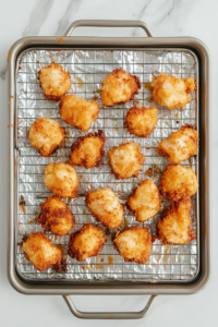 This image shows crispy, golden-brown fried chicken being transferred to a wire rack, allowing excess oil to drain for a perfect crunch.