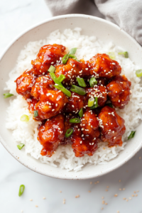 This image shows Chang’s Spicy Chicken served over a bed of fluffy rice, garnished with white sesame seeds and fresh green onions for the perfect finishing touch.