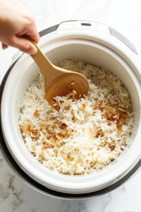 This image shows uncooked rice being poured into the slow cooker, ready to absorb the flavors of the broth, vegetables, and seasonings.
