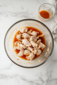 This image shows buttermilk and hot sauce being poured over the seasoned chicken, creating a rich marinade.