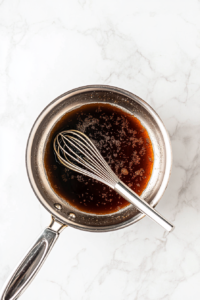 This image shows a saucepan with ingredients being combined to create the base of a homemade sweet and sour sauce.