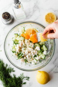 This image shows seasonings being sprinkled over the whitefish salad to enhance its flavor.