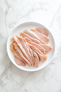 This image shows sliced turkey being warmed in a microwave-safe dish inside a microwave, ensuring it is heated through before assembling the sandwich.