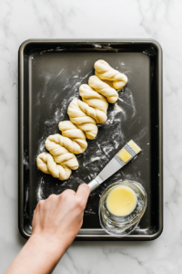 This image shows a close-up of crescent dough being sliced into even strips and carefully twisted to create the signature shape of cinnamon crescent twists.