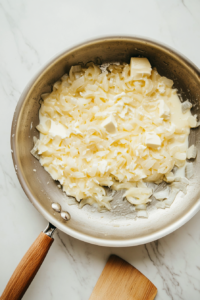 This image shows diced onions being sautéed until soft, with cream cheese melting into the mixture, creating a rich and flavorful filling base.