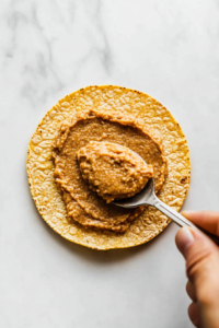 spreading-creamy-refried-beans-on-a-crispy-tostada