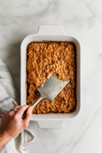 This image shows the seasoned turkey meatloaf mixture being pressed evenly into a prepared baking pan, forming the base layer of the casserole.