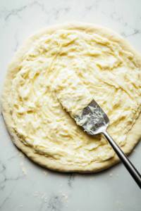 This image shows a creamy cheese filling being evenly spread over the babka dough, ensuring a flavorful and rich filling in every bite.