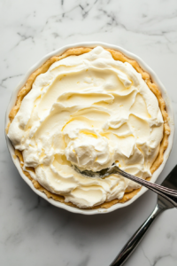 This image shows a thick layer of fluffy whipped cream being spread over fresh strawberries, creating a creamy and airy topping.