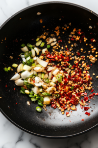 This image shows golden-brown chicken pieces being returned to the wok, soaking up the rich flavors of the sautéed aromatics.
