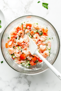 This image shows a bowl of creamy ingredients being mixed together, creating the rich base for the crab and shrimp dip.