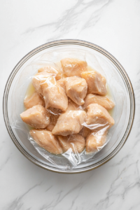 This image shows chicken pieces resting in a bowl of seasoned buttermilk marinade, allowing the flavors to penetrate and tenderize the meat.