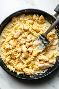 This image shows rotini pasta and seasoned chicken being mixed into the creamy ranch sauce, ensuring every bite is flavorful.