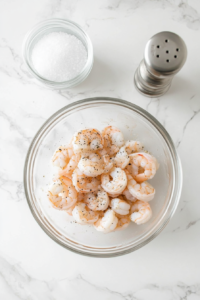 This image shows raw shrimp being coated with a blend of seasonings, ensuring every bite is packed with flavor before cooking begins.