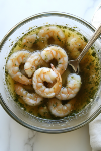 This image shows raw shrimp being coated in a vibrant cilantro lime marinade, ensuring they absorb all the fresh and tangy flavors before cooking.