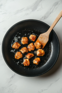 This image shows fully cooked, golden-brown chicken pieces being removed from the skillet and set aside, ready to be added back into the pasta dish.