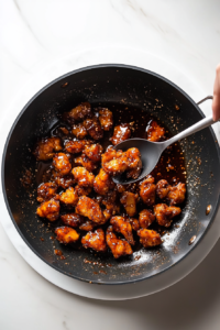This image shows perfectly browned chicken pieces being removed from a pot and placed onto a plate, ready to be added back into the stew later for a tender and flavorful finish.