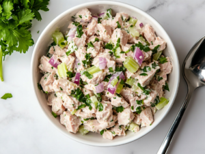This image shows a fresh tuna salad served in a white bowl, seasoned with salt, pepper, and a squeeze of lemon juice for brightness.
