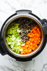 This image shows fresh carrot pieces and wild rice being added to an Instant Pot, creating the base for a hearty and nutritious meal.