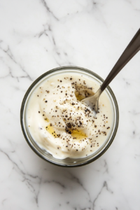 This image shows a top-down view of a small bowl with red wine vinegar mayo being whisked together, creating a creamy and tangy spread for the turkey melt sandwich.