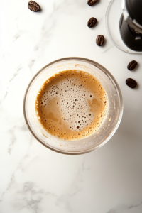 This image shows the coffee mixture being vigorously whisked until it becomes thick, airy, and forms soft, frothy peaks, perfect for whipped coffee.