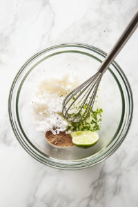 This image shows a bowl of marinade being whisked together, featuring fresh lime juice, garlic, and cilantro for a zesty and aromatic shrimp wrap seasoning.