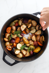 This image shows a hand sprinkling a mix of dried dill, paprika, salt, and black pepper into the soup, enhancing its rich and aromatic flavor.