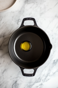This image shows a black pot on the stove with a thin layer of shimmering oil, preparing the base for a rich and flavorful soup.