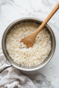 This image shows uncooked white rice being added to a saucepan and toasted until lightly golden, enhancing its texture and flavor.