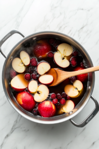 This image shows fresh fruit being added to the boiling water, starting the process of infusing flavors for the sweet and fruity Kompot.