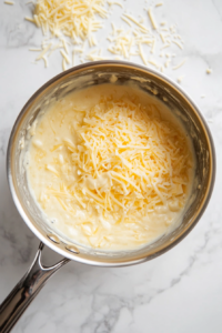 blending-shredded-cheddar-and-grated-parmesan-into-the-cheese-sauce-for-extra-flavor