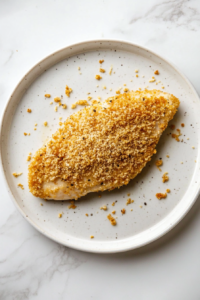 This image shows breaded chicken resting on a wire rack before cooking, allowing the coating to set for an extra crispy and even fry.