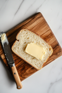 buttering-the-first-slice-of-bread-for-a-rich-crispy-crust