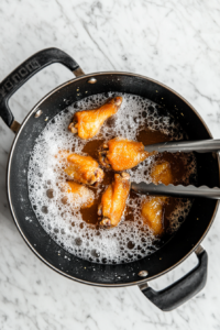 This image shows chicken wings sizzling in hot oil, turning golden brown and crispy.