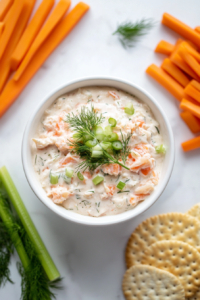 chilled-crab-dip-served-with-crackers-aThis image shows a beautifully plated cold crab dip in a white bowl, surrounded by crispy crackers and garnished with thin lemon slices and fresh dill, making for a perfect appetizer spread.and-garnished-with-lemon-slices-and-fresh-dill