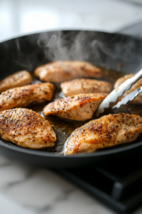 This image shows chicken searing in a skillet, developing a golden-brown crust.