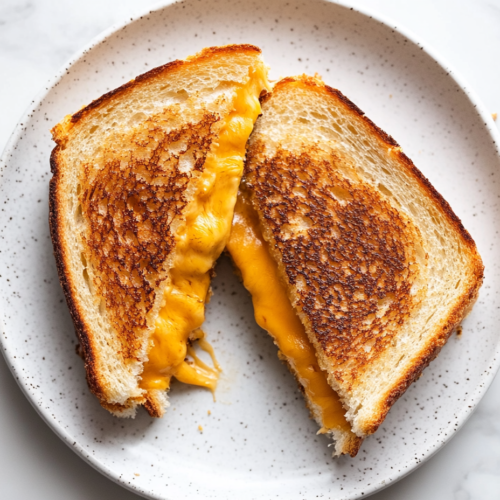 crispy-golden-brown-grilled-cheese-sandwich-filled-with-melted-cheese-on-a-white-plate
