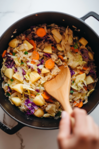 This image shows fresh diced potatoes, vibrant orange carrot slices, and fragrant minced garlic being stirred into the pot, adding depth and heartiness to the dish.