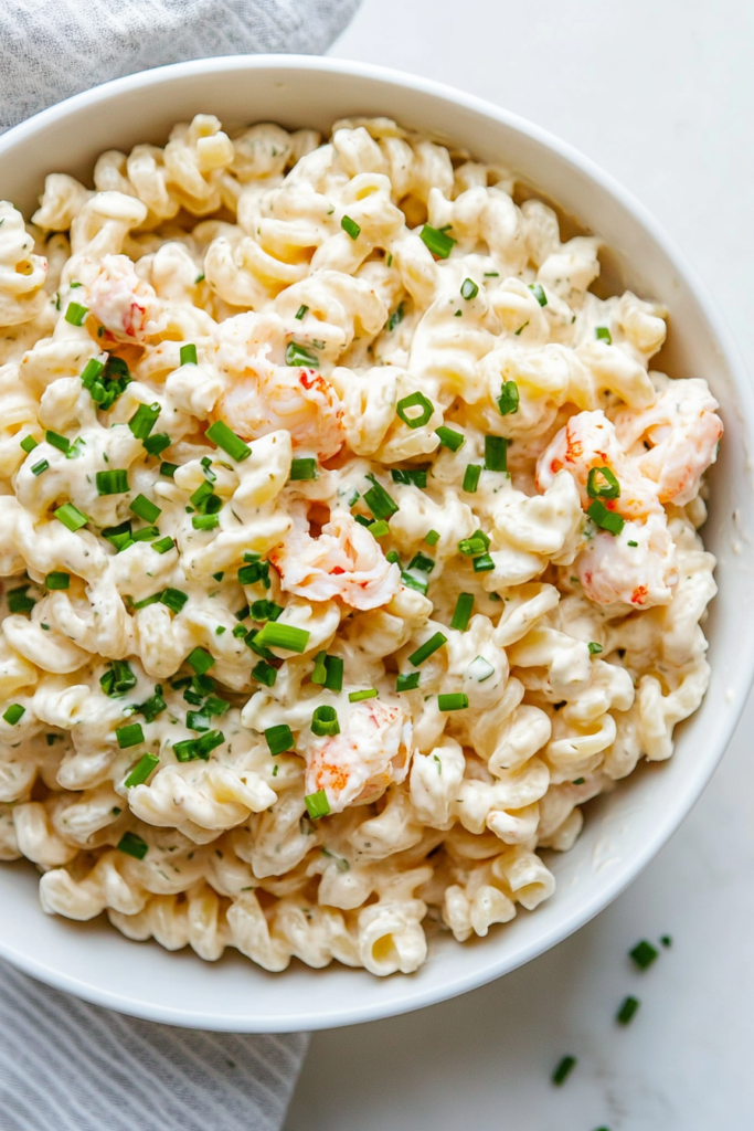 This image shows a beautifully prepared crab pasta salad garnished with finely chopped fresh chives, adding a pop of green color and a burst of fresh, herby flavor to the dish.
