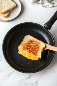 flipping-the-grilled-cheese-to-achieve-a-crispy-golden-brown-finish