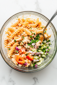 freshly-cooked-pasta-combined-with-crab-peas-celery-onions-and-bell-peppers-in-a-large-mixing-bowl