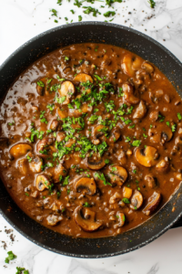 This image shows Mushroom Masala being garnished with freshly chopped coriander, adding a fresh and aromatic touch to the creamy, flavorful dish.